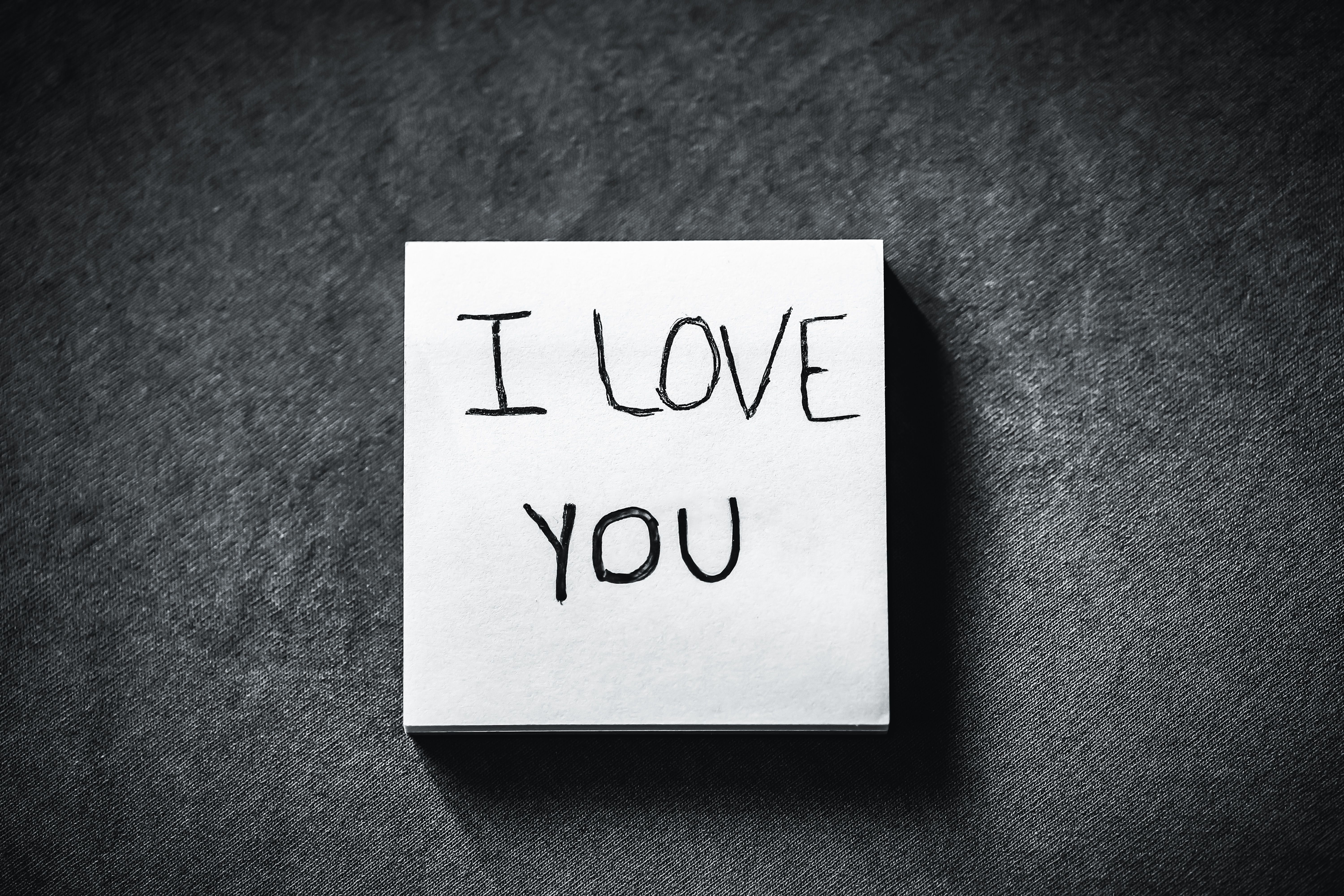 Close-up of a handwritten 'I Love You' message on a note, expressing love.