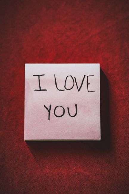 Romantic handwritten note with I Love You message on a vibrant red surface.