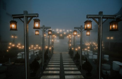 Free Enchanting misty pathway illuminated by lanterns at night, creating a serene and mystical atmosphere. Stock Photo