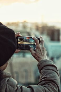 An adult taking a cityscape photo at sunset with a smartphone in Rabat, Morocco.