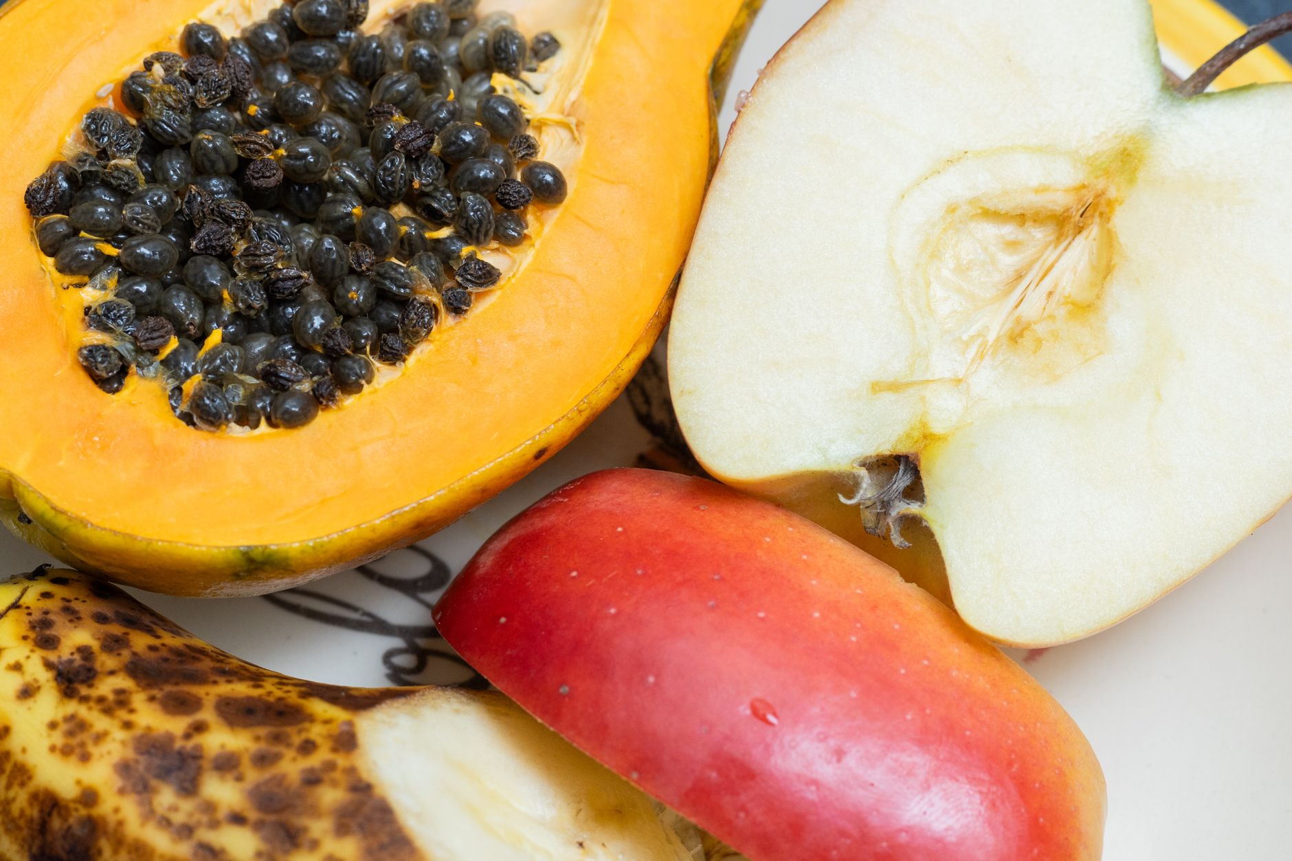 What Is Food Combining For Weight Loss? 1 Close-up of cut papaya, apple, and banana on a plate, vibrant and healthy.