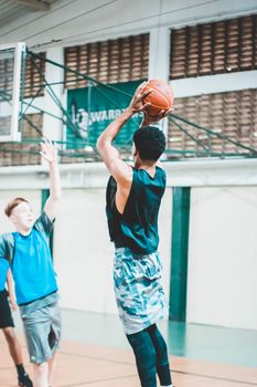 Dynamic indoor basketball match showcasing players in action, jumping to make a shot.