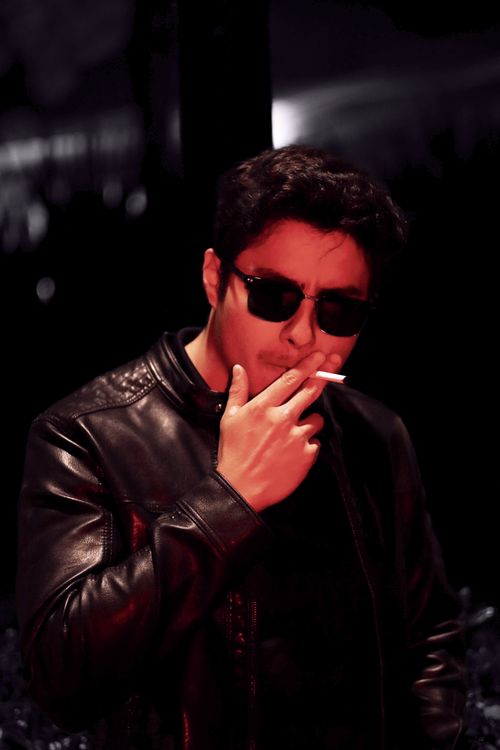 Free Man wearing sunglasses and leather jacket, smoking at night outdoors. Stock Photo