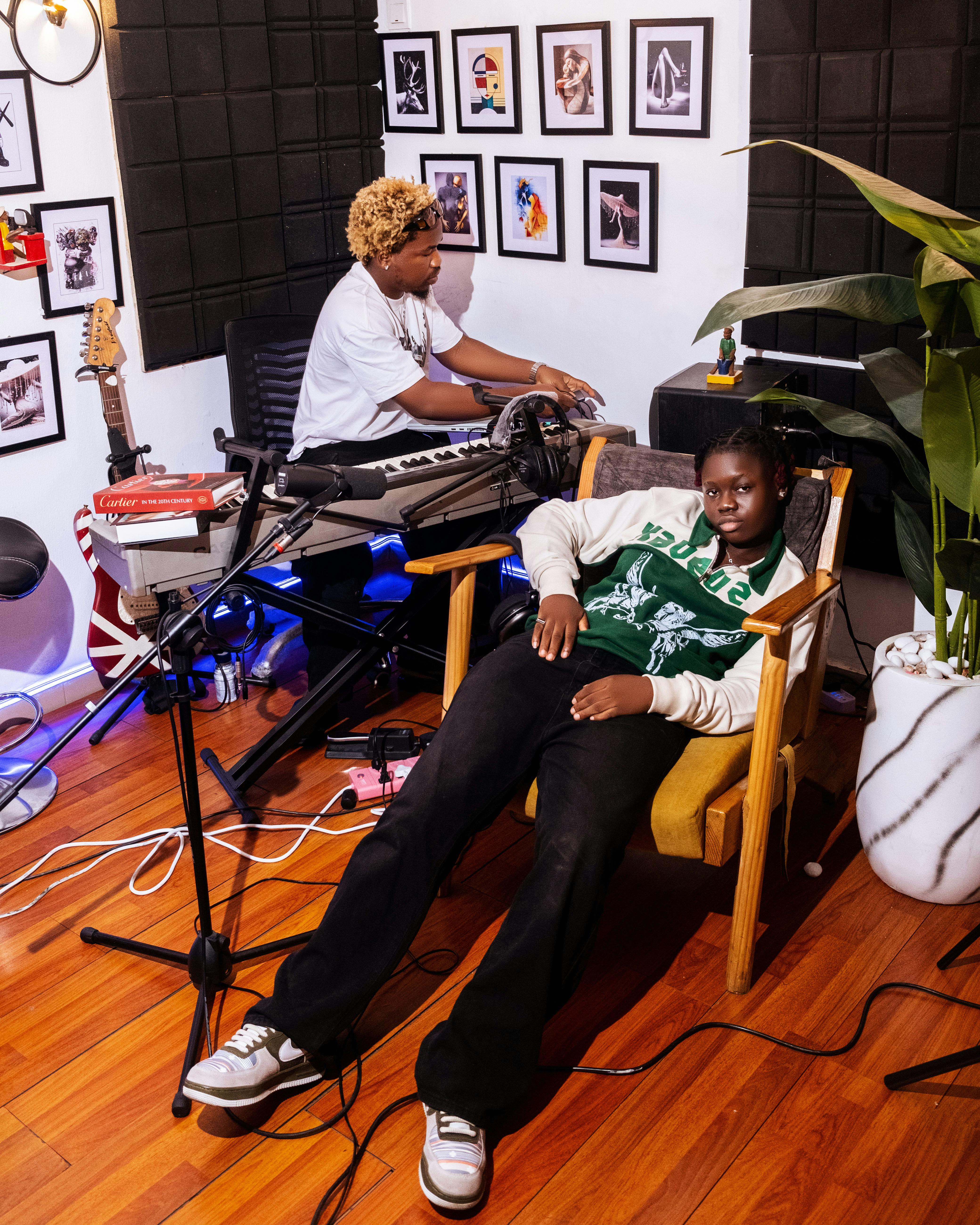 Two musicians in a home studio setting, surrounded by instruments and decor.