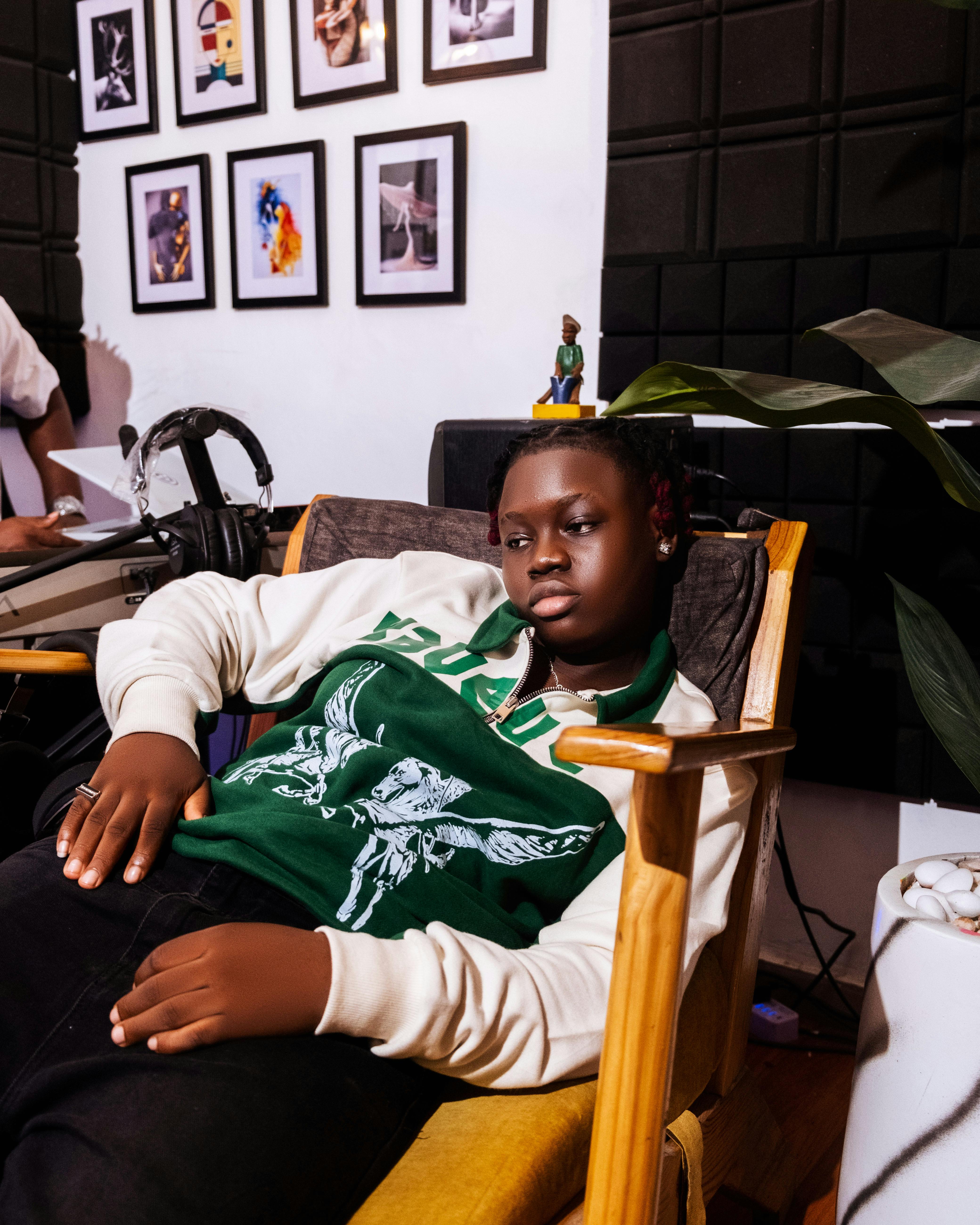 Teen resting in artsy studio with framed photos and plants, exuding calm.