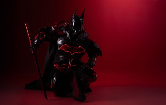 Striking image of Batman cosplay featuring a sword in dramatic red lighting.