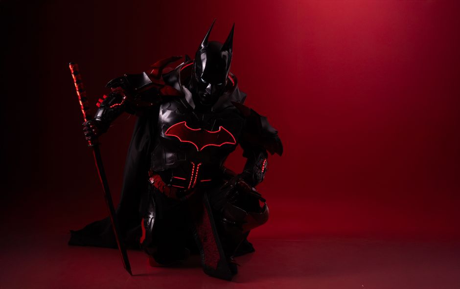 Striking image of Batman cosplay featuring a sword in dramatic red lighting.