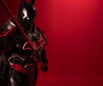 Striking image of a Batman cosplay with a red background, exuding power and mystery.
