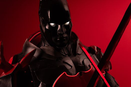 Striking cosplay portrait featuring a character in black and red armor with a dramatic red background.