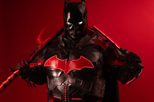 Dramatic Batman inspired cosplay featuring black and red armor against a vibrant red background.