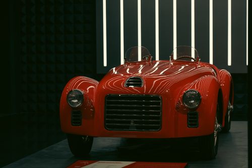 Free A vintage red sports car displayed in a modern showroom with sleek lighting. Stock Photo