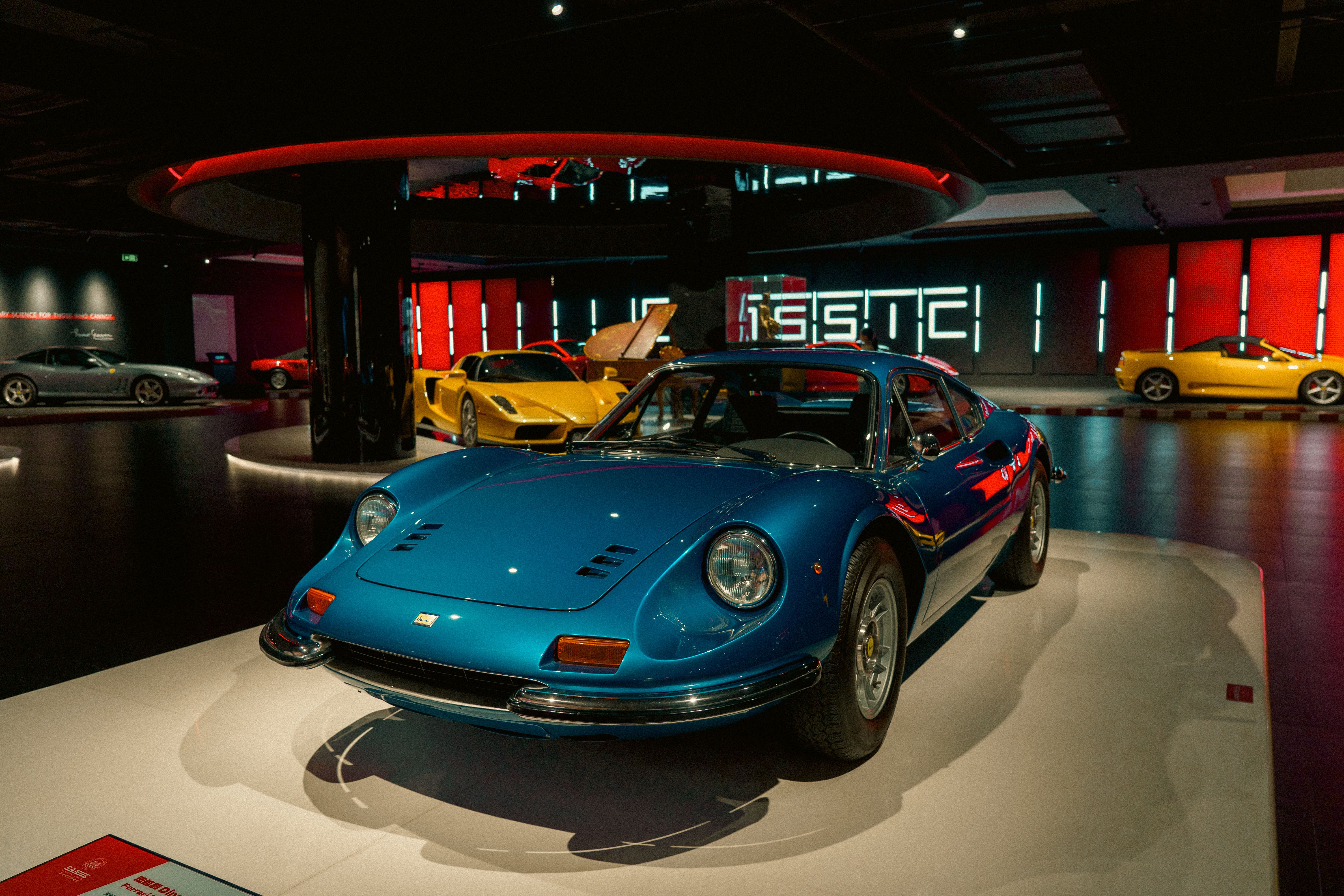 Vintage blue sports car on display in a modern showroom with ambient lighting