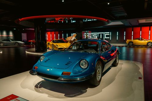 Free A vintage blue sports car displayed in a sleek, modern indoor showroom with ambient lighting. Stock Photo