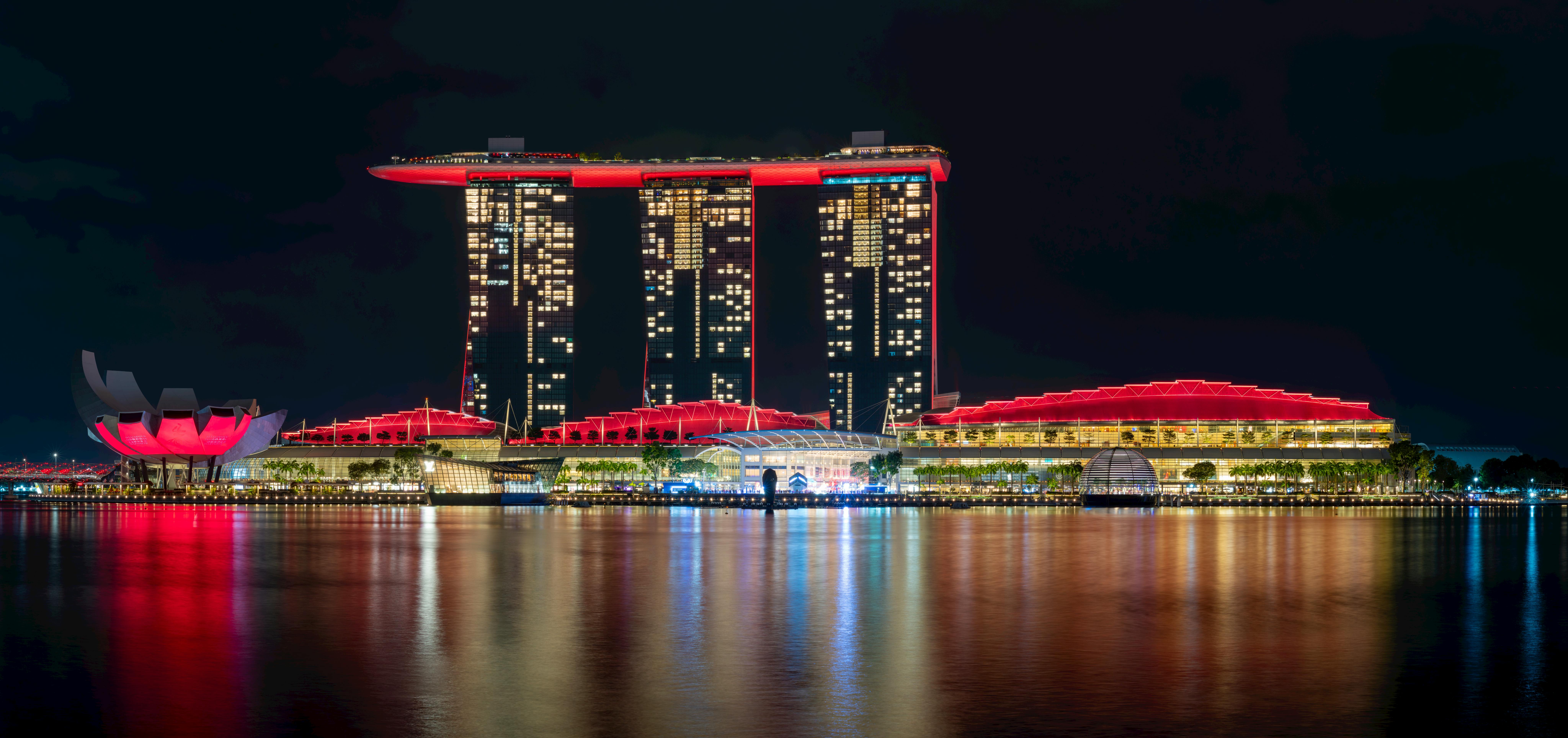 Stunning night view of Marina Bay Sands with vibrant red lighting reflecting on the water.