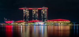 Stunning night view of Marina Bay Sands with vibrant red lighting reflecting on the water.