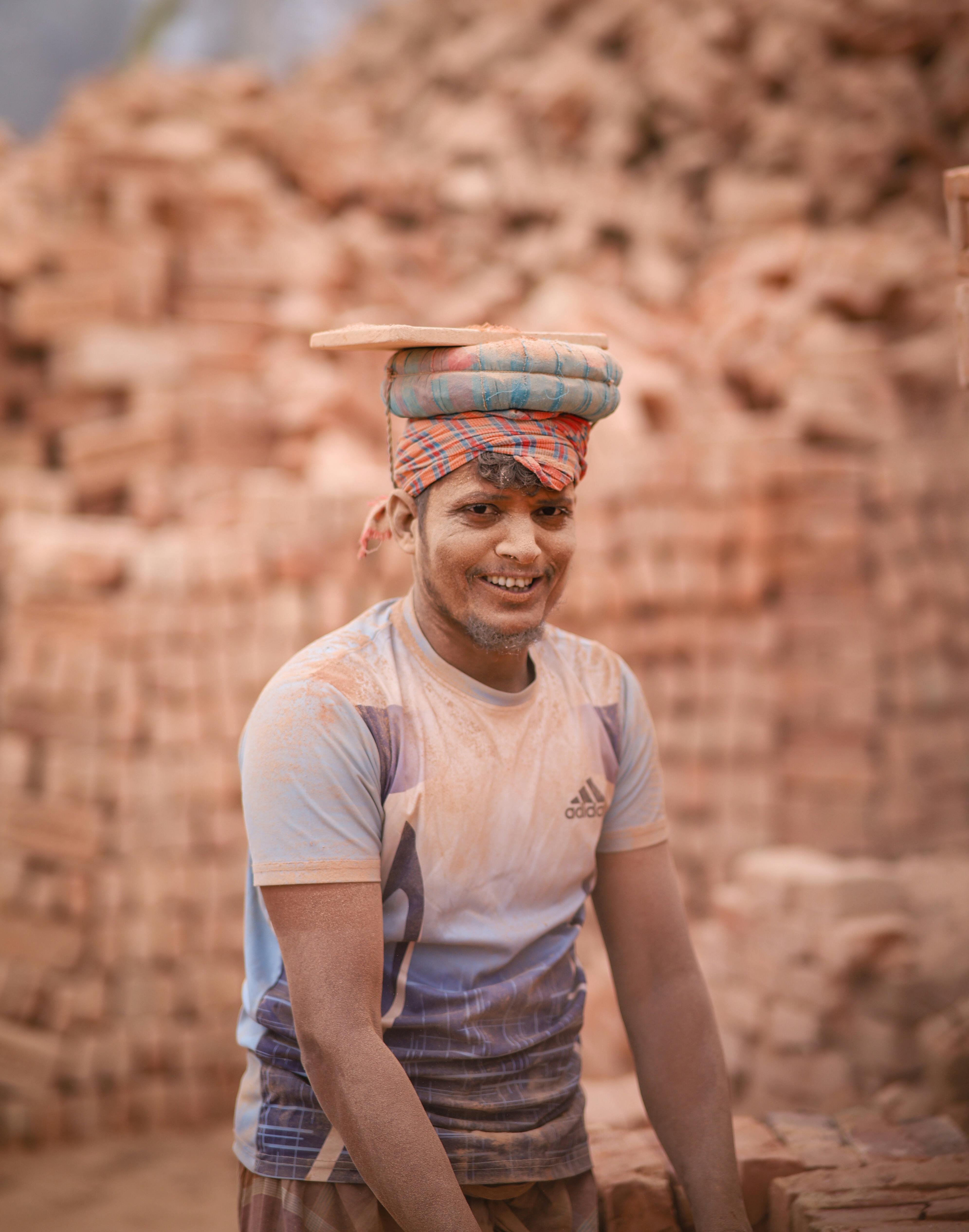 Happy worker carrying bricks at a construction site with a smile.