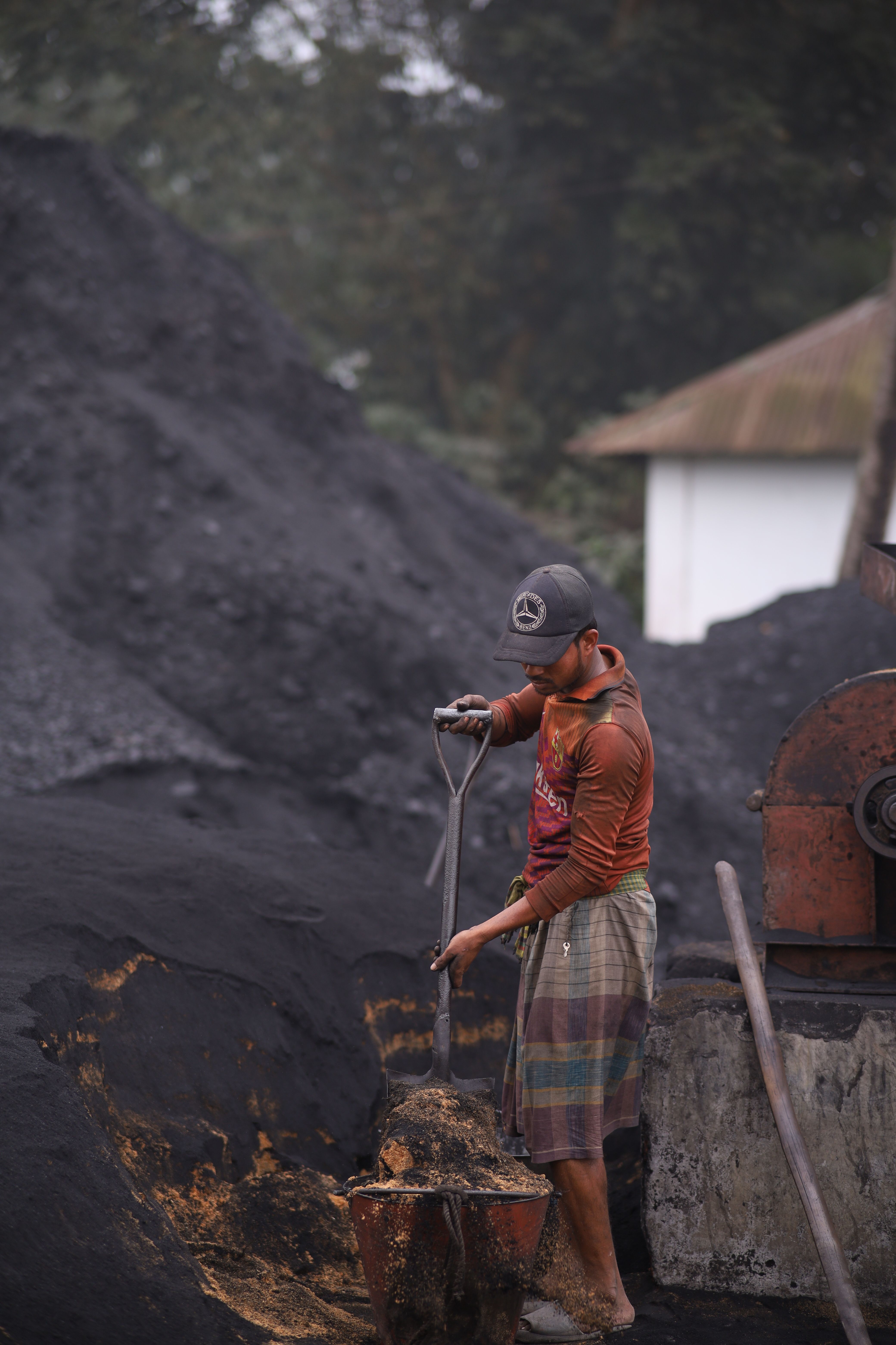 Laborer Shoveling Coal at Industrial Site · Free Stock Photo