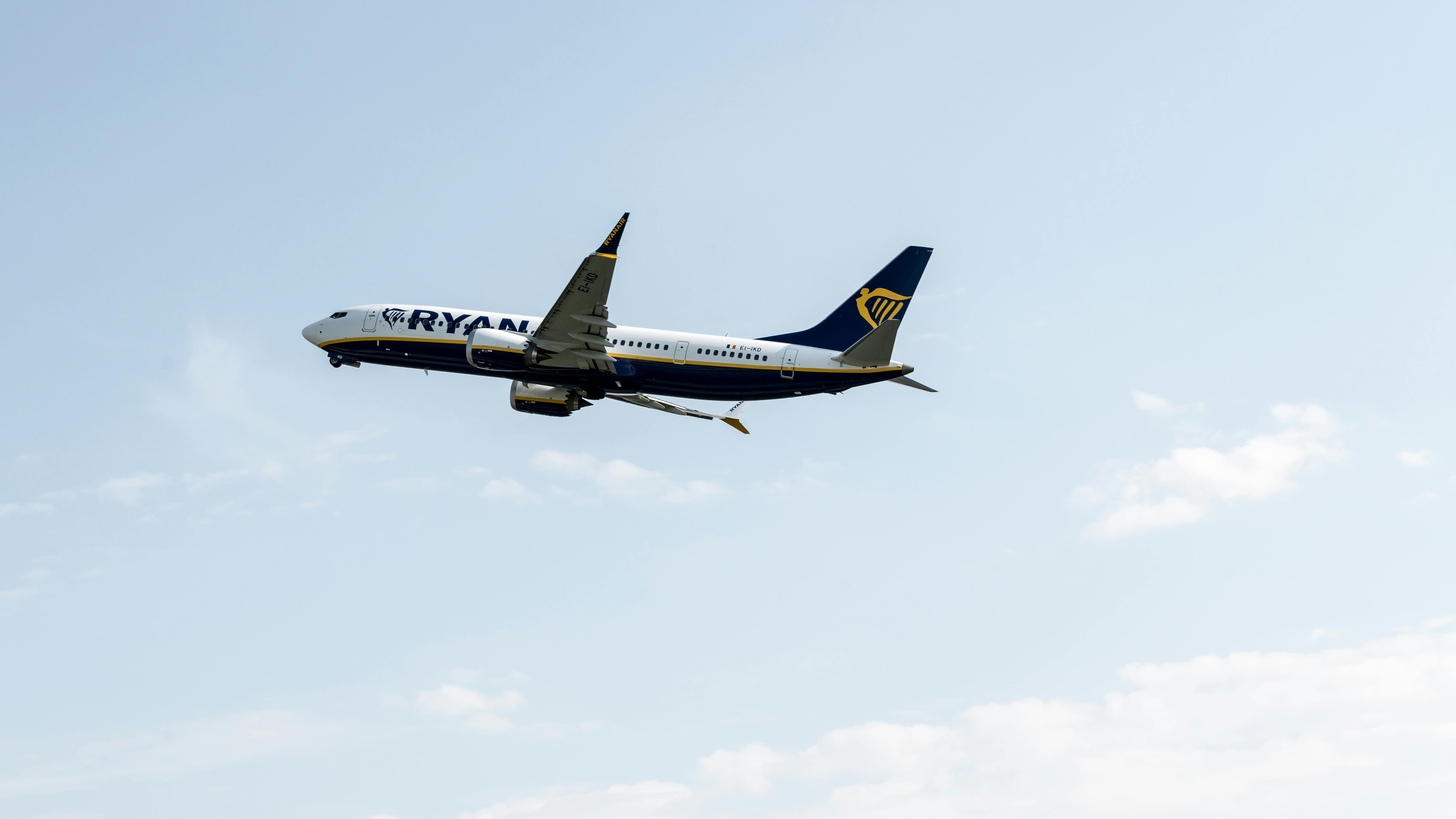 A Ryanair plane captured mid-flight against a clear sky at Prague Airport.