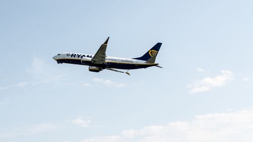 Free A Ryanair plane captured mid-flight against a clear sky at Prague Airport. Stock Photo