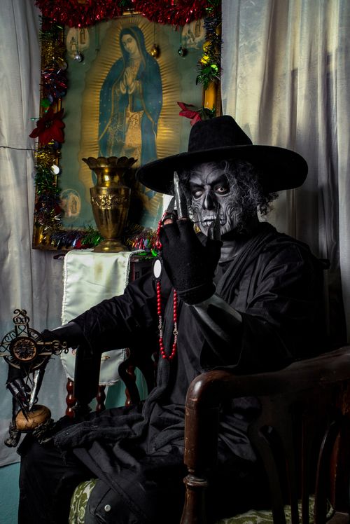 Free A person in skeleton costume with religious iconography and dark atmosphere. Stock Photo