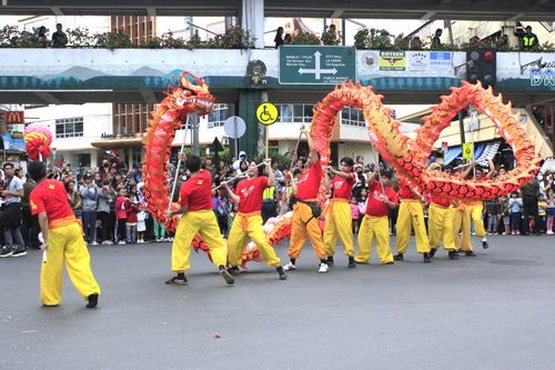 Free Traditional dragon dance performed by a lively group during a street festival, attracting many onlookers. Stock Photo