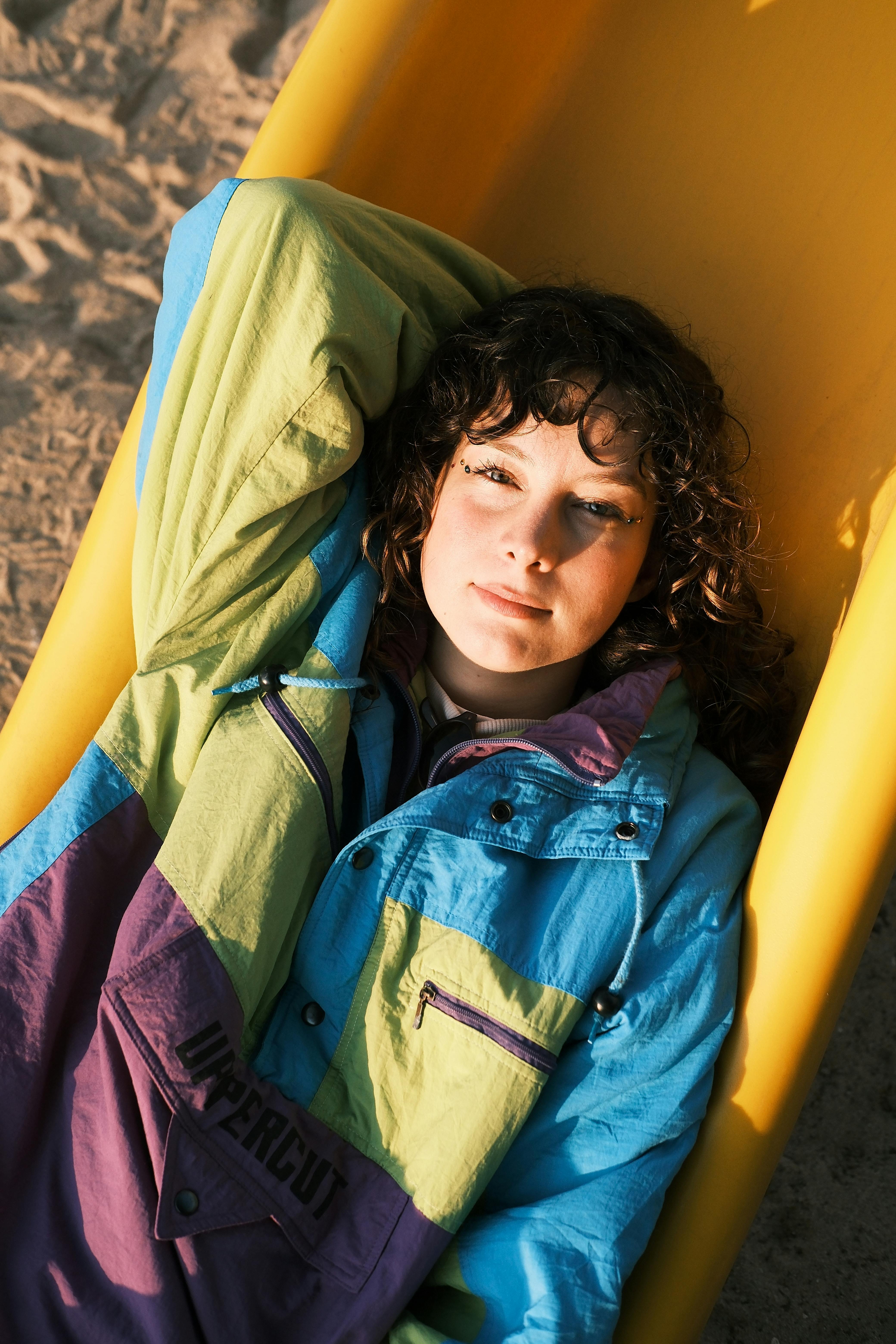 A relaxing young woman in retro fashion jacket enjoys the beach sun.