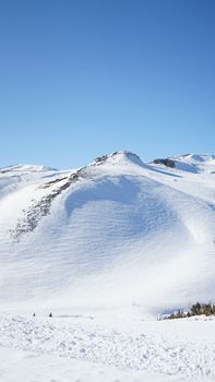 Scenic view of snow-covered mountains under a clear blue sky in Mavrovo, North Macedonia.