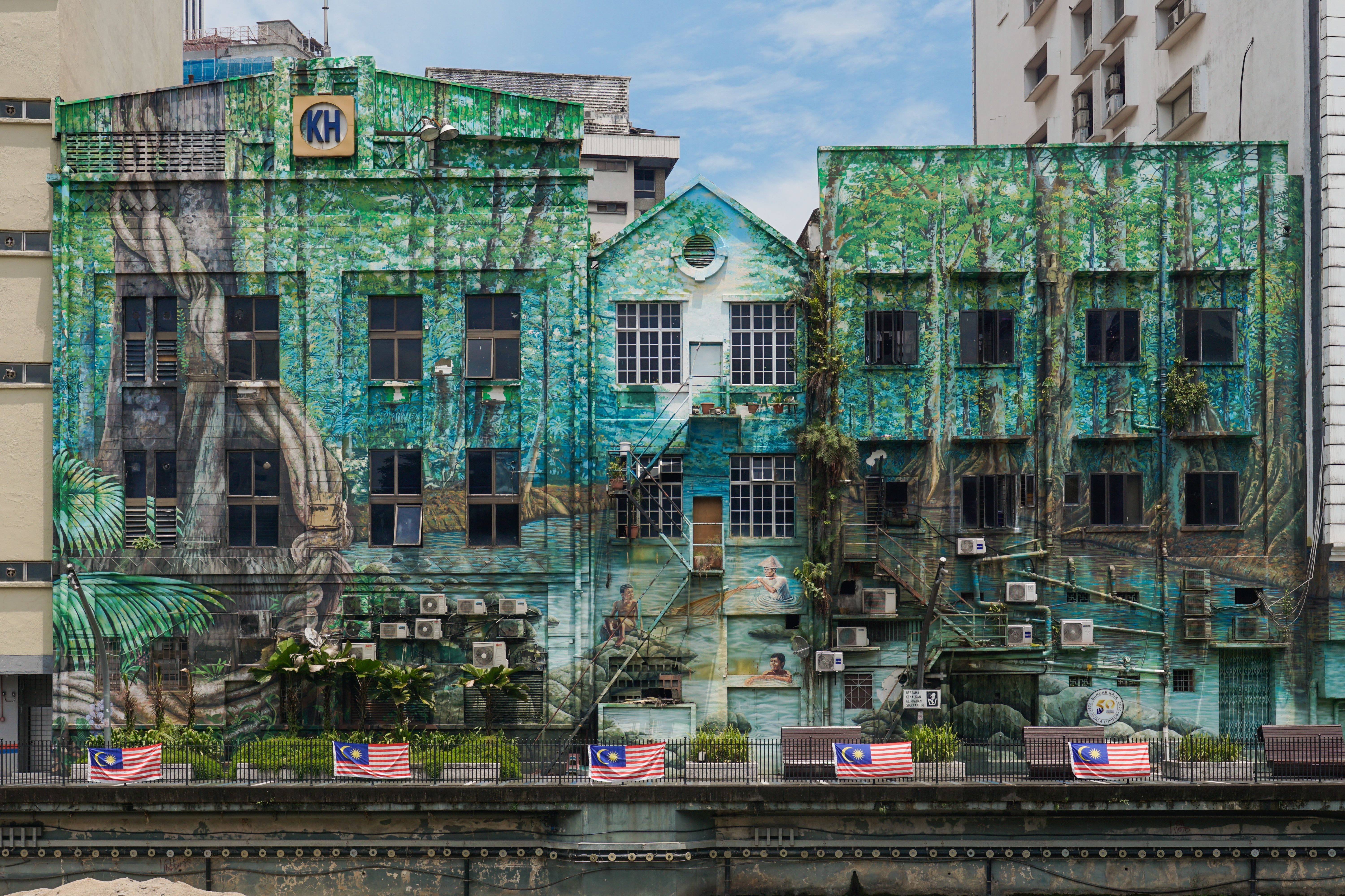 Colorful building mural in Kuala Lumpur, featuring lush greenery and Malaysian flags.