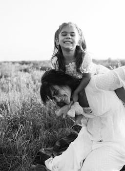 Black and white photo of mother and daughter laughing in a field.