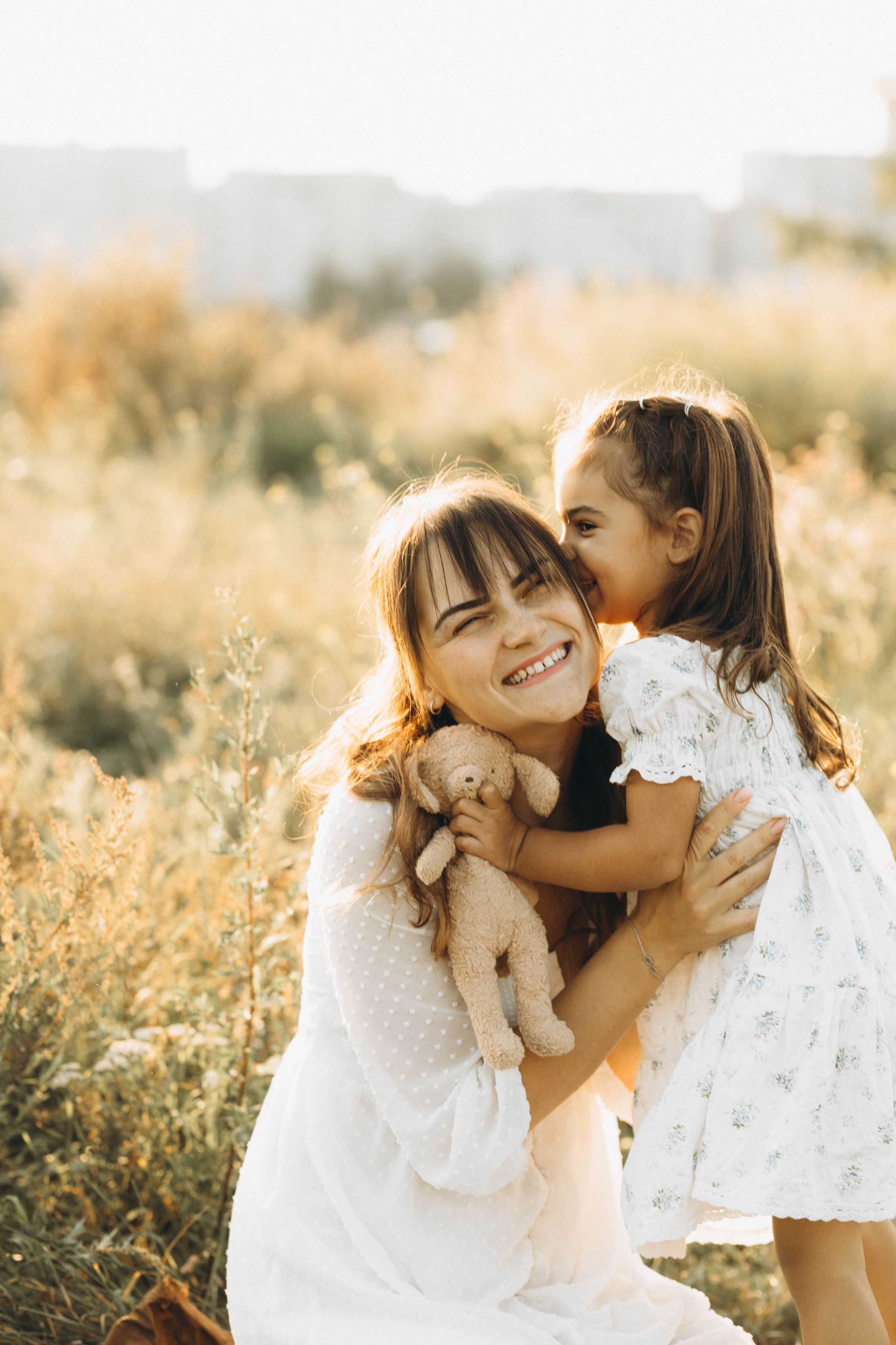 Happy mother and daughter sharing a joyful moment in a sunlit meadow.