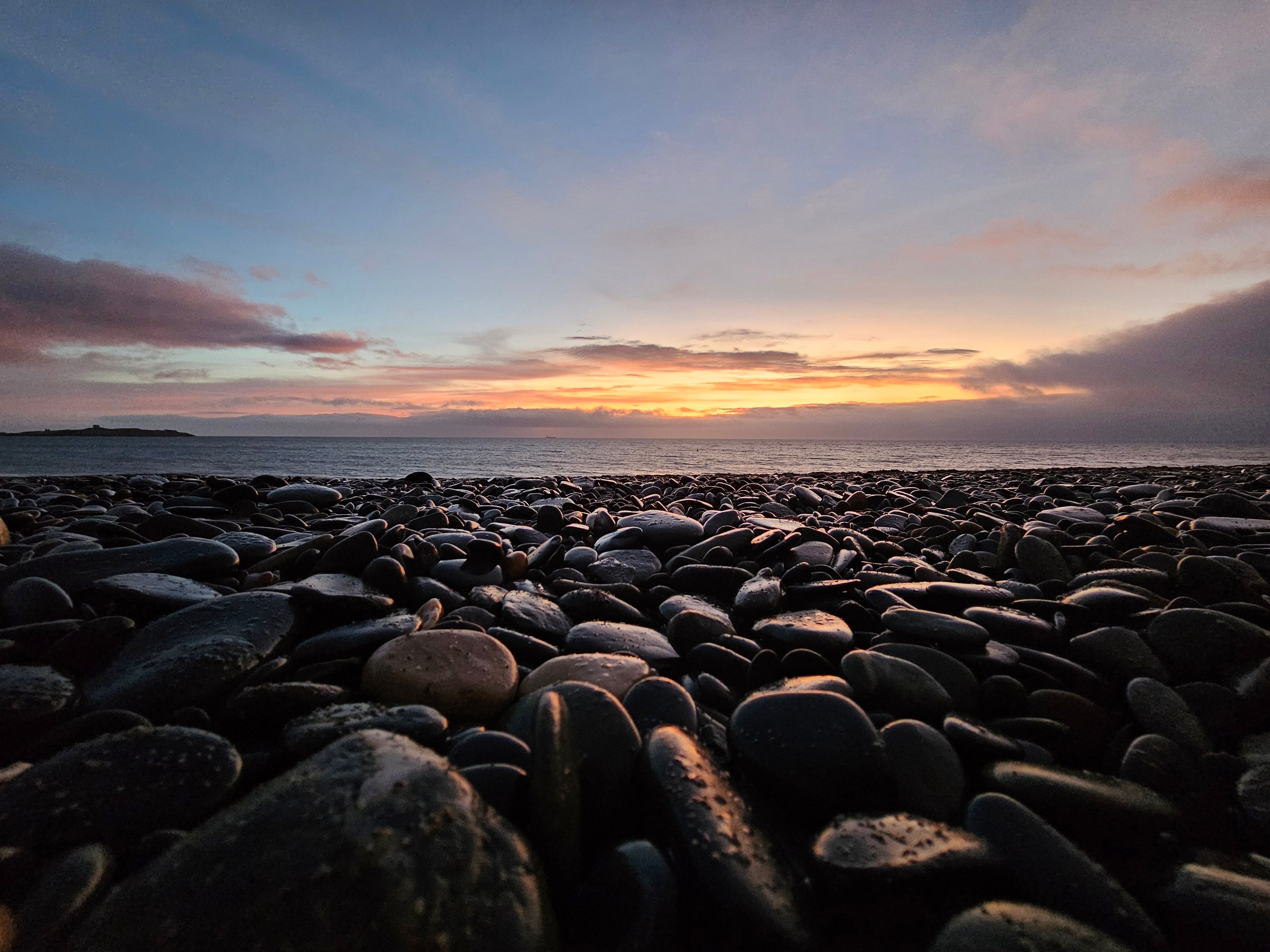 Tranquil sunrise view over a pebble-strewn beach in Dublin, Ireland.