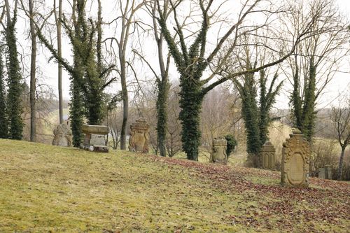Free An ancient cemetery with weathered gravestones surrounded by barren winter trees, creating a serene and timeless scene. Stock Photo