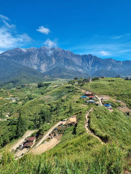 Free Breathtaking view of lush green hills and a towering mountain under a vivid blue sky. Stock Photo