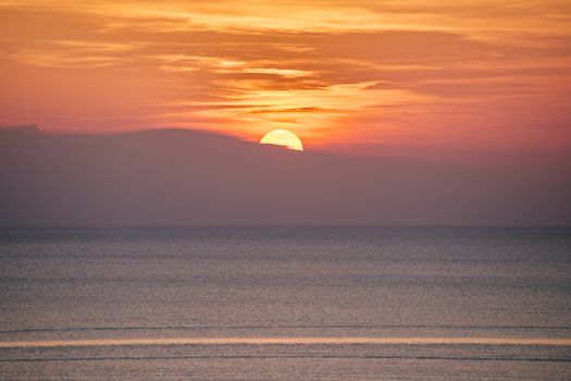 A beautiful sunset over the calm ocean with vibrant colors in the sky.