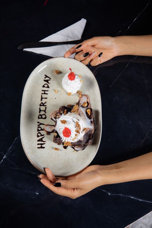 Free Top view of a decorated birthday dessert plate with hands holding it. Stock Photo