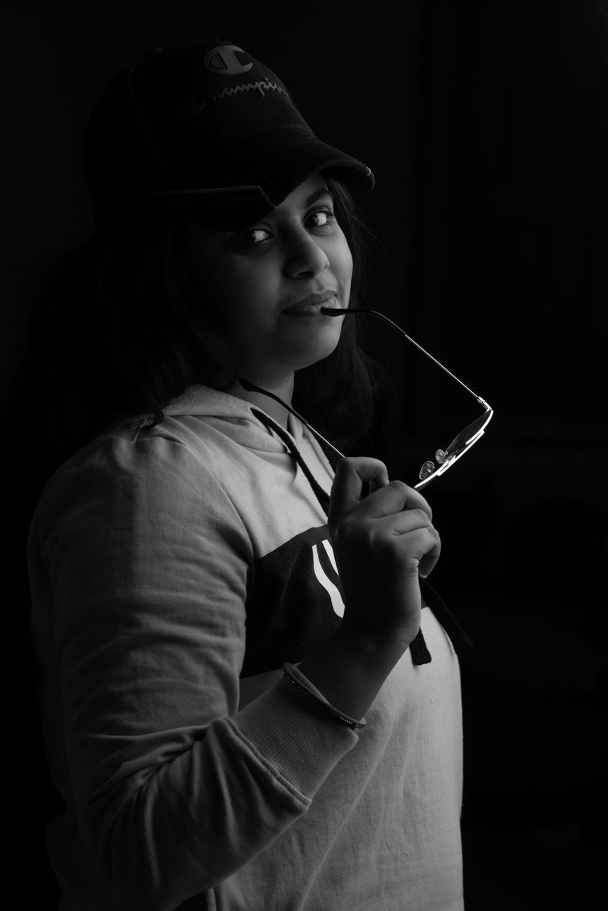 Stylish black and white portrait featuring a woman posing with sunglasses, conveying a modern and mo