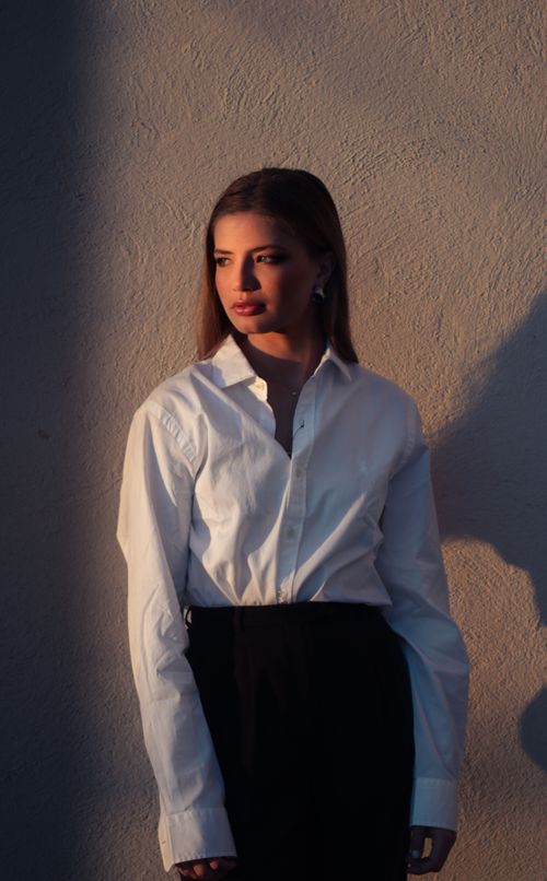 Free Stylish woman in white blouse against textured wall, dramatic lighting. Stock Photo