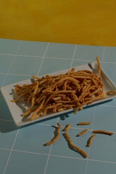 Delicious crispy snack sticks on a white plate with blue and yellow background for a tasty treat scene.
