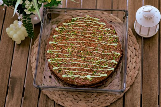 Top view of a chocolate cake with pistachios and cream drizzle, perfect for celebrations.
