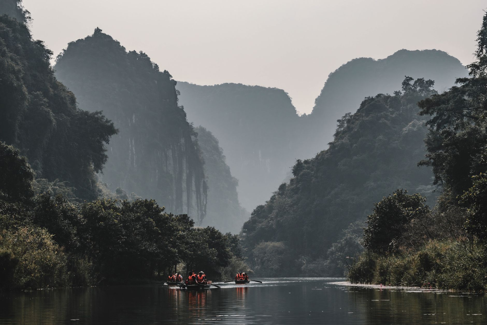 Canoeing through scenic limestone mountains under a serene sky.