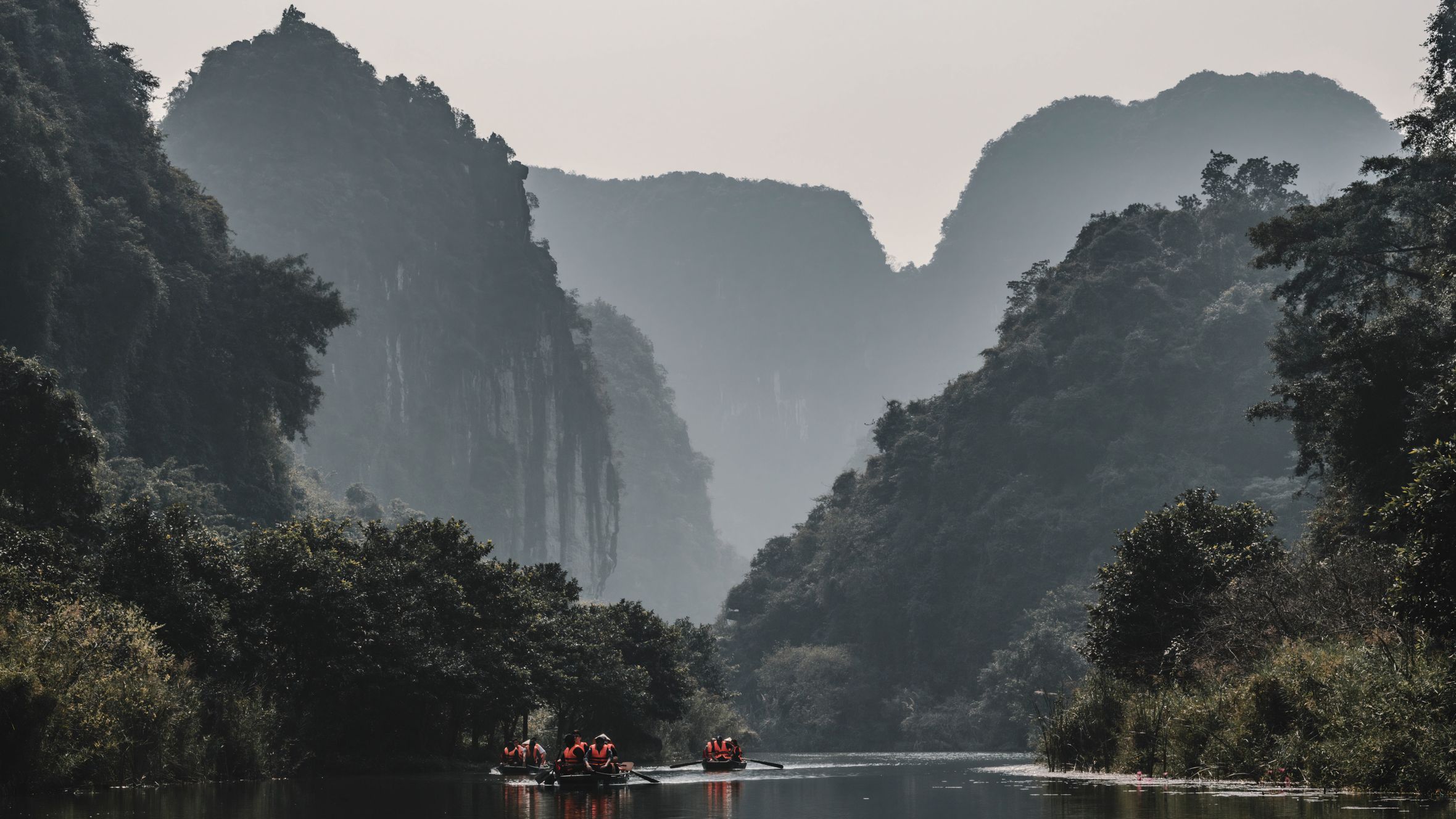 Canoeing through scenic limestone mountains under a serene sky.