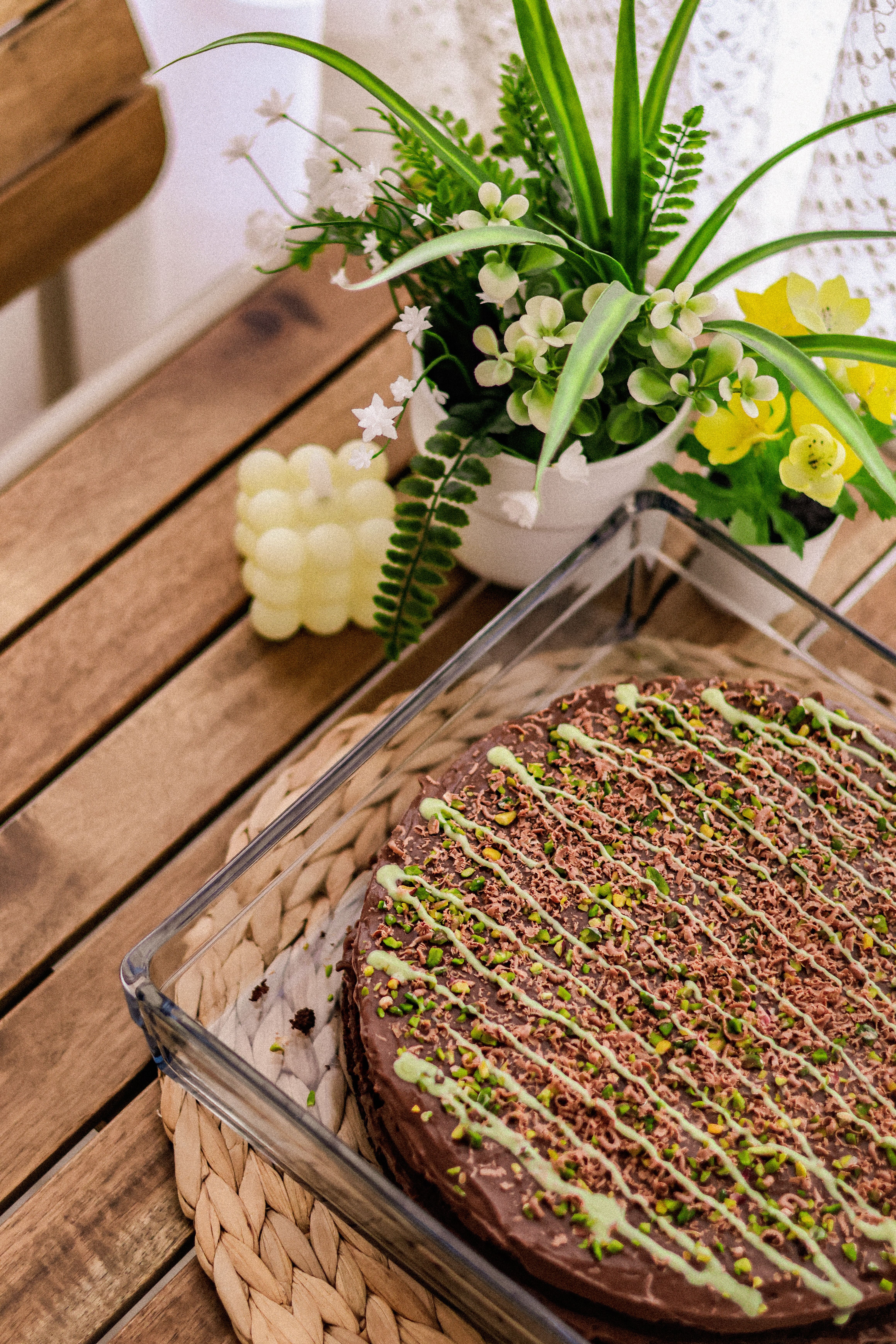 Delicious homemade chocolate cake in rustic setting with decorative green pistachio drizzle.