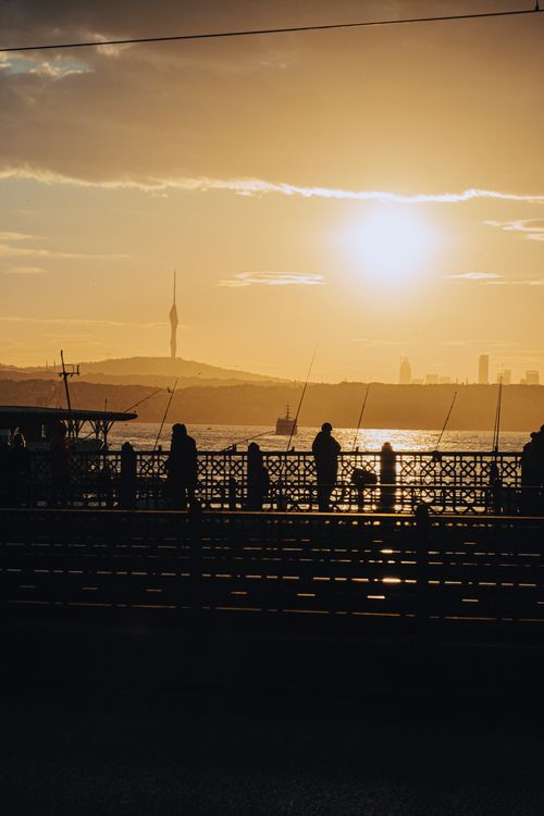 Free Silhouetted figures fishing at sunset on the Galata Bridge with the Istanbul skyline. Stock Photo