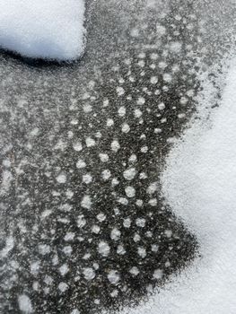 Close-up of snow-covered ice with unique patterns, emphasizing winter's artistic touch.