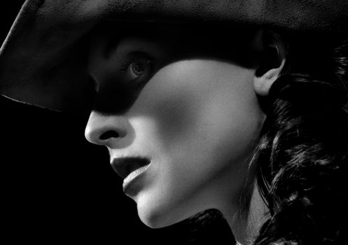 Artistic black and white profile portrait of a woman in a hat.