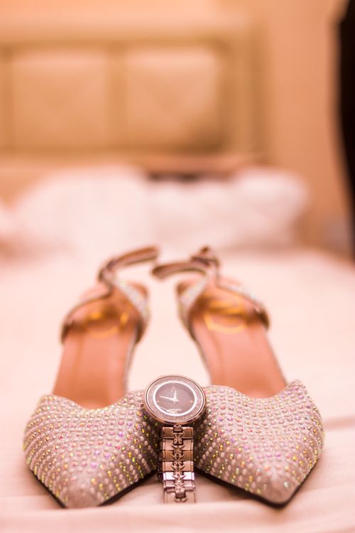 Free Close-up of jeweled bridal shoes and a watch, symbolizing elegance and time. Stock Photo
