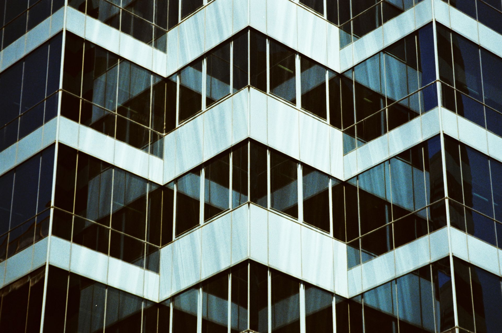 Close-up of a geometric facade on a modern office building with reflective glass windows.
