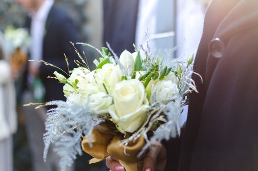 Close-up of a beautiful wedding bouquet with white roses at an outdoor ceremony.