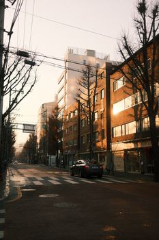 Serene urban street with car and buildings at sunset creating a warm cityscape vibe.
