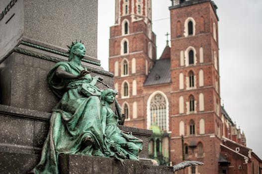 Statue with Kraków's Mariacki Church in the background, highlighting European architecture.